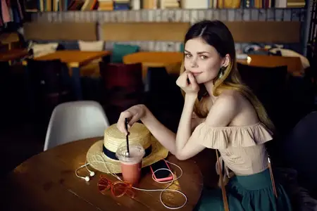 Симпатичная женщина с книгой в руках в кафе, стильная