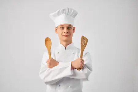 Шеф-повар с кухонной утварью профессионально работает на кухне ресторана