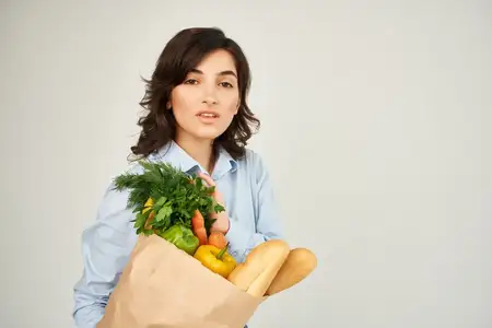 Брюнетка с пакетом продуктов из супермаркета: здоровая еда, овощи