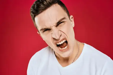 Мужчина в белой футболке с недовольным выражением лица на изолированном фоне