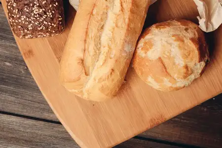 Мучные изделия: буханка хлеба на деревянной доске, светлый фон