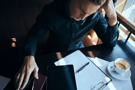 Бизнесмен-фрилансер работает в кафе с ноутбуком, общается по телефону