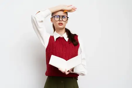 Молодая женщина с задумчивым выражением лица стоит с раскрытой книгой в руках