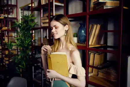 Красивая женщина с книгой в руках отдыхает в кафе