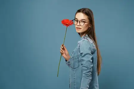 Девушка с цветком возле лица, в очках, глянцевый крупный план