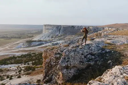 Женщина стоит на краю обрыва, наслаждаясь красотой природы и приключением
