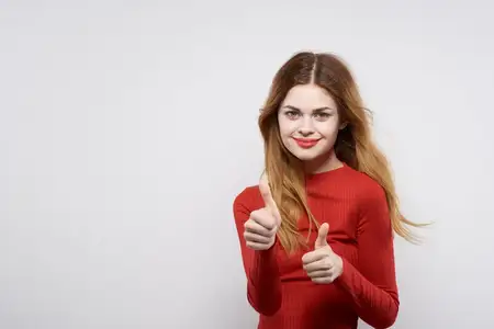 Весёлая женщина с привлекательной внешностью, причёской и макияжем на светлом фоне