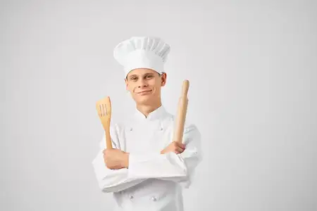 Мужчина-повар в униформе работает на кухне ресторана, занимаясь приготовлением пищи