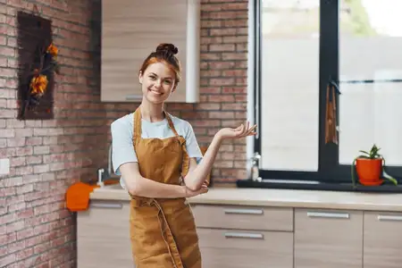 Женщина в фартуке на кухне занимается домашними делами