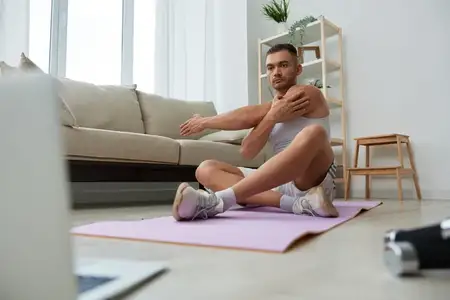 Мужчина занимается спортом, смотрит запись тренировки на телефоне и повторяет упражнения