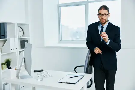 Мужчина-менеджер в офисе жестикулирует руками, работая за компьютером