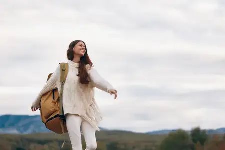 Горное приключение: улыбающаяся женщина на скале, наслаждающаяся природой и свободой