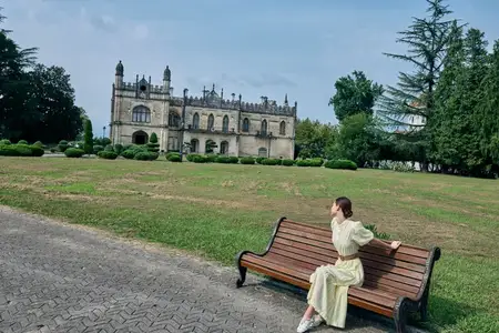 Женщина на скамейке в парке у поместья, историческое платье, аутентичность, инклюзивность