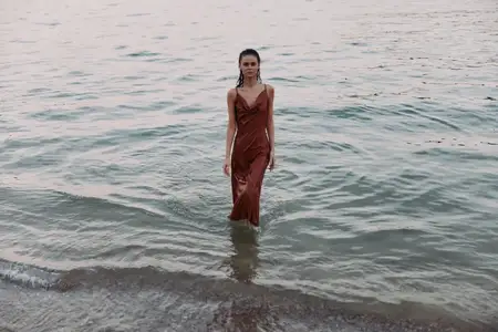 Мягкие волны лижут берег, а солнечный свет играет на воде, создавая мрачную, задумчивую сцену, подходящую для повествования о моде, путешествиях или образе жизни