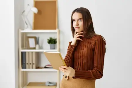 Девушка-подросток сидит за столом дома и готовится к экзамену