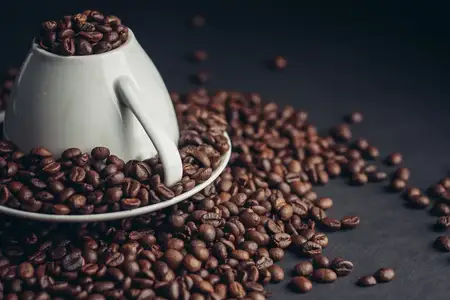 Белое блюдце и чашка кофе на сером столе, крупный план