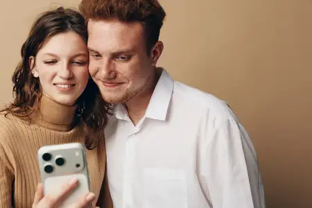 Счастливые молодые мужчина и женщина со светлой кожей делают селфи на смартфон