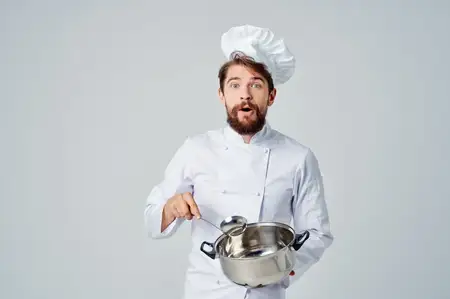 Повар готовит еду в кастрюле на кухне, занимаясь кулинарной работой