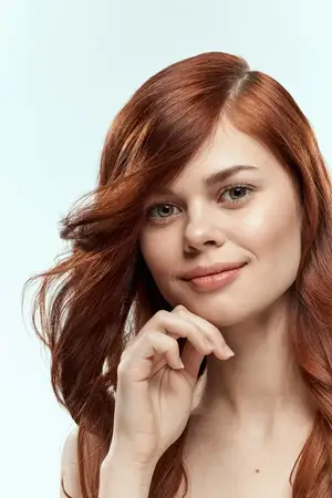 Симпатичная женщина держится за волосы, улыбается, косметика, образ жизни, обнаженные плечи, прическа, забота, очарование, светлый фон