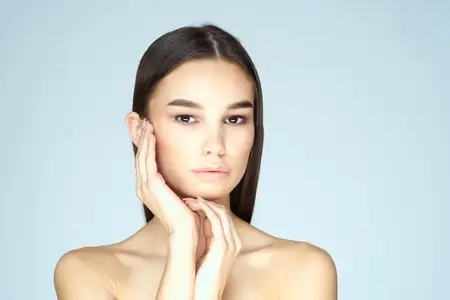 Женщина с обнаженными плечами и длинными волосами на синем фоне