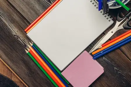 Блокноты, канцелярские принадлежности и карандаши на деревянном столе