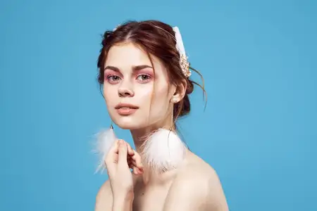 Женщина с пушистыми серьгами, обнаженные плечи, гламур, синий фон