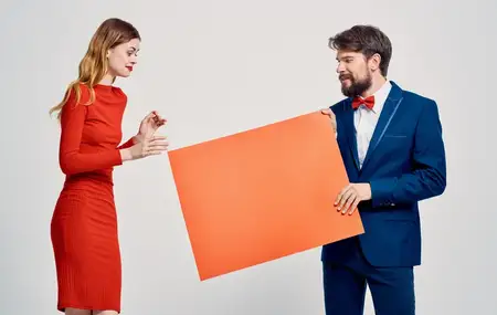 Энергичный мужчина с макетом и эмоциональная женщина на светлом фоне, реклама шоу-бизнеса