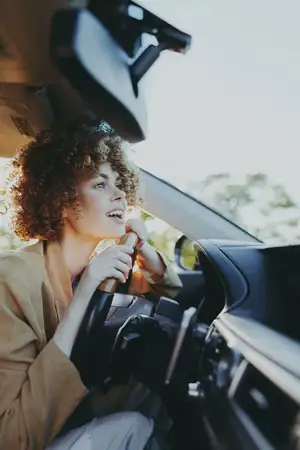 Ретро-цветовые тона подчеркивают жизнерадостную водительницу в салоне автомобиля, передавая аутентичность, повседневные путешествия и юношескую энергию в лайфстайл-изображении