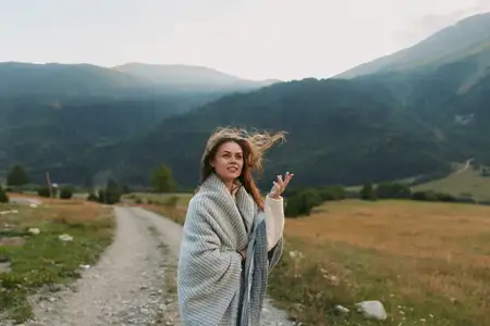 Портрет в стиле life-style: женщина в мягкой накидке на фоне горного пейзажа, передающий чувство свободы, исследования и спокойствия на широких просторах природы