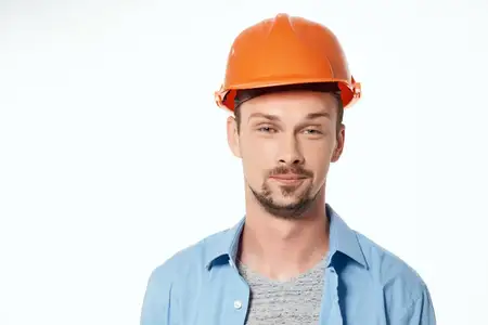 Мужчина в оранжевой защитной каске, рабочая профессия