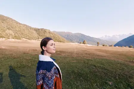Женщина в куртке, сфотографированная на горном лугу