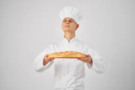 Мужчина в поварской одежде, профессионал с багетом в руках, свежий продукт, работа