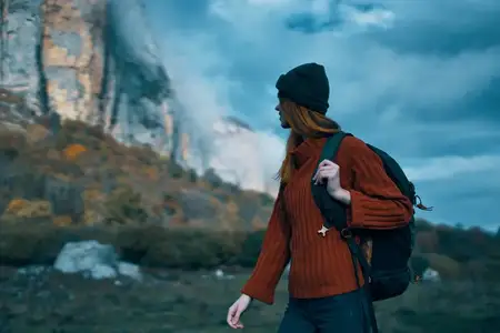 Путешественница в свитере с рюкзаком за спиной, туризм, облака, небо, пейзаж