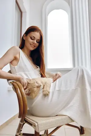 Красивая женщина гладит кошку, сидящую на стуле на открытом воздухе