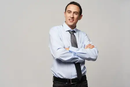 Мужчина в рубашке и галстуке скрестил руки на груди