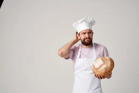 Мужчина в форме пекаря печет хлеб