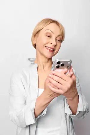 Улыбающаяся пожилая женщина держит смартфон