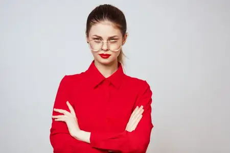 Симпатичная женщина в красной рубашке, с укладкой, макияжем и в очках, излучает моду и шарм