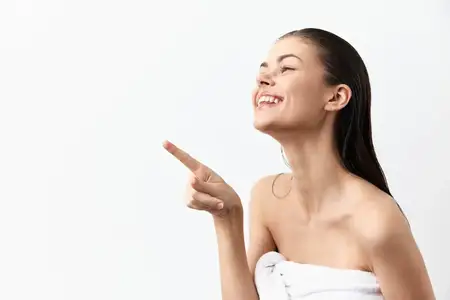 Радостная женщина с длинными мокрыми волосами ярко улыбается, указывая в сторону