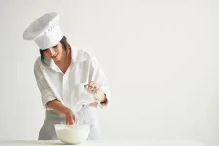 Женщина-пекарь работает с тестом на кухне, готовя выпечку