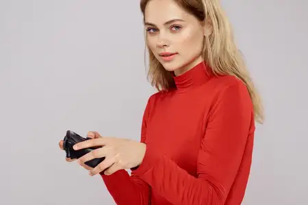 Женщина с геймпадом в руках, играет в игры, эмоции, образ жизни, досуг, красная рубашка, светлый фон