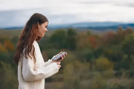 Горное блаженство: улыбающаяся женщина наслаждается свободой и приключениями на природе, делая походное селфи в киберпространстве
