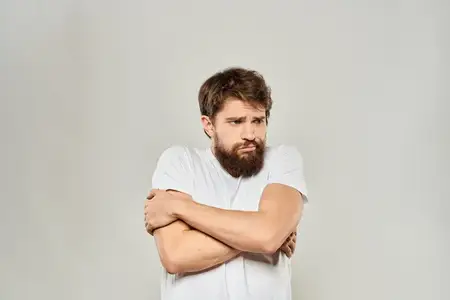 Мужчина в белой футболке жестикулирует руками в студии, выражая недовольство