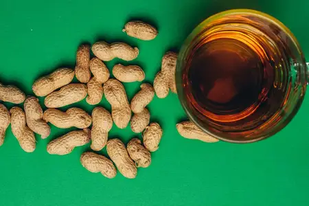 Пиво и арахис в скорлупе, бар, алкоголь на зелёном фоне