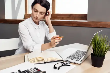 Женщина сидит за своим рабочим столом в офисе перед ноутбуком, работает профессиональный руководитель