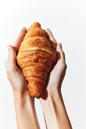 Руки держат круассан на белом фоне