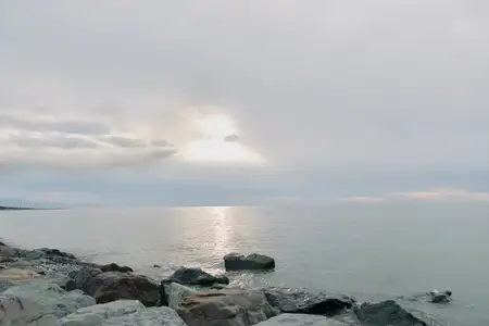 Каменистая береговая линия и спокойный океан под пасмурным небом