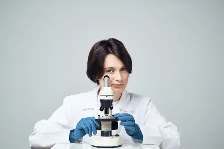 Женщина-лаборант работает с микроскопом, занимаясь научными исследованиями в студийных условиях