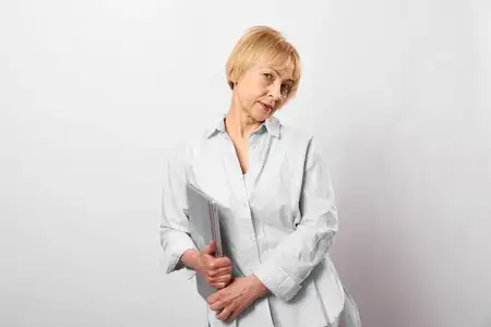 Пожилая женщина в помещении держит книгу