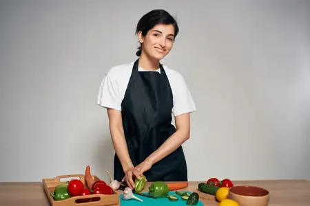Женщина в черном фартуке, овощи на кухне, здоровая еда